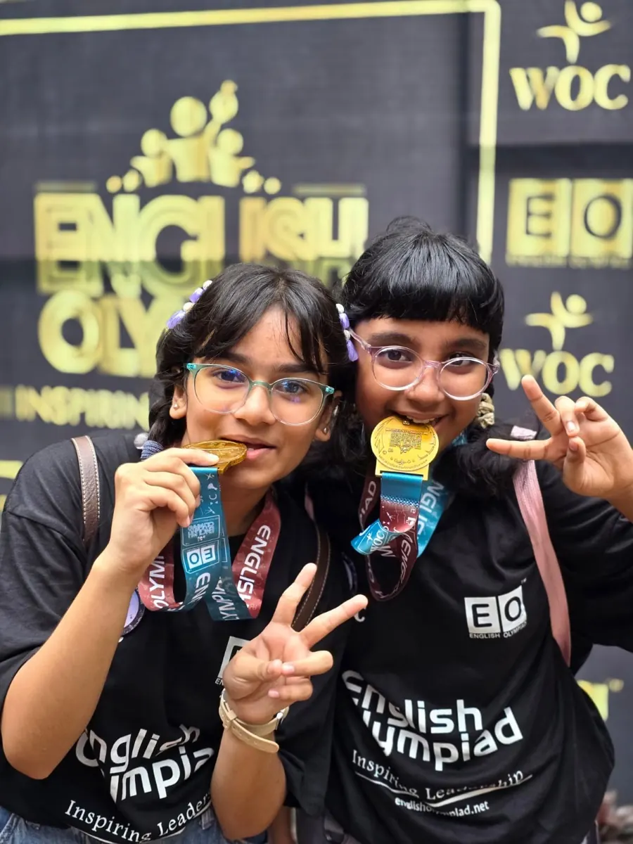 Two young English Olympiad champions celebrating with their Medals for Excellence